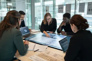Professionals collaborating around a digital table in a modern innovation lab, intently discussing digitized heritage archives in natural light.